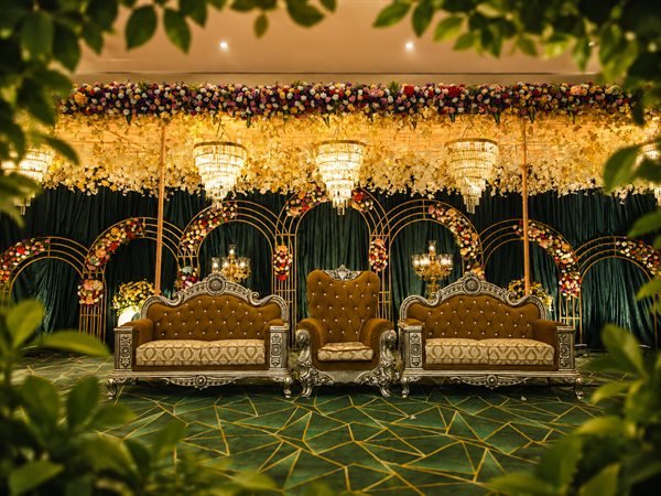 Majestic floral arch stage setup with golden twin thrones